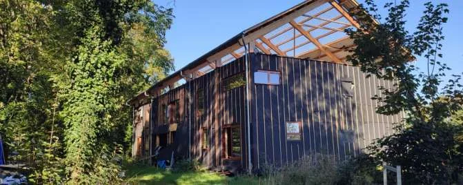 Le bâtiment en ossature bois, bardé et couvert, dans la verdure