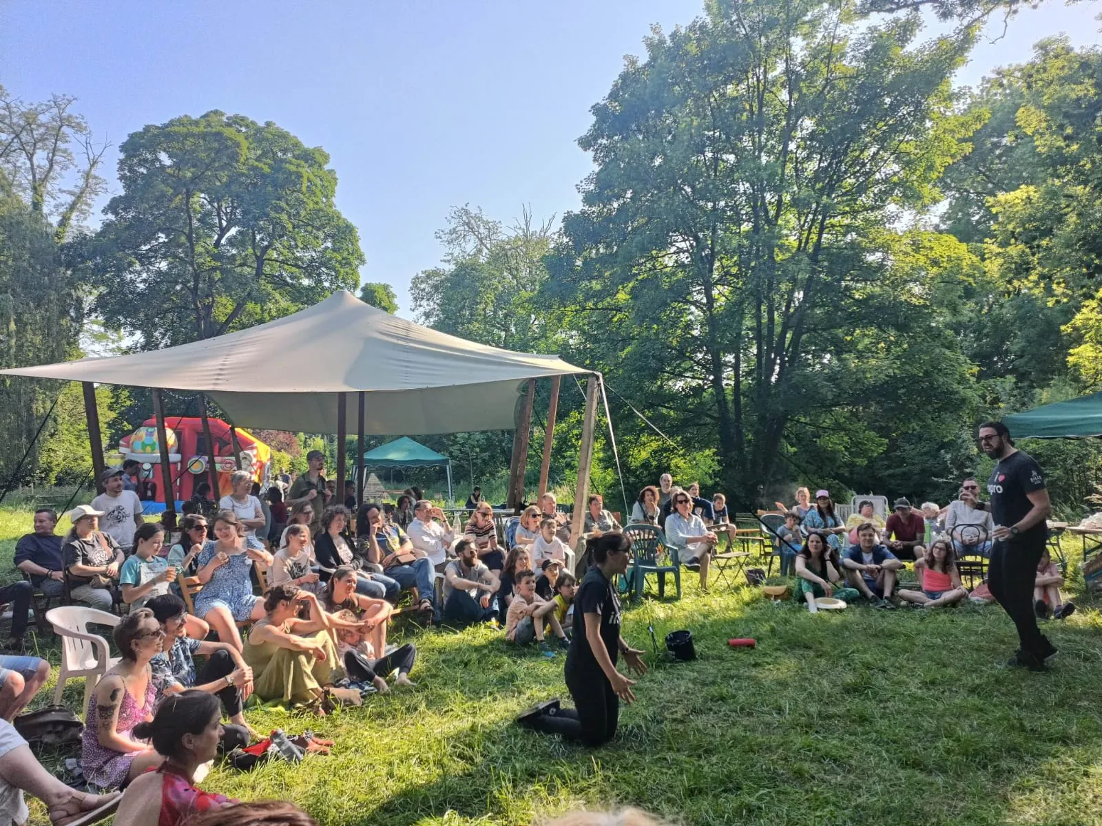 Public assis dans l'herbe devant un spectacle d'improvisation